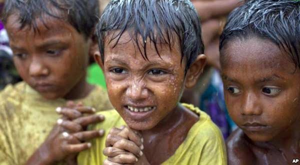 Internally displaced Rohingya boys shiver in rain in a makeshift camp for Rohingya people in Sittwe, Burma.