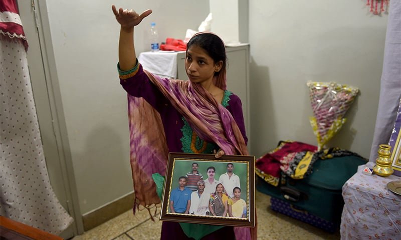 Deaf-mute Indian woman, Geeta holds a photograph of a family in India which she believes is her family, during an AFP interview at the Edhi Foundation in Karachi. — AFP