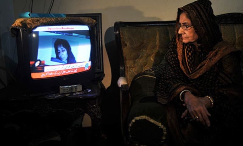 Ismat Siddiqui, the mother of US-detained Pakistani woman Aafia Siddiqui, watches a news channel after a court verdict in Karachi. — AFP/File