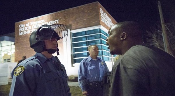 A protester confronts a police officer outside the City of Ferguson Police Department and Municipal Court in Ferguson, Missouri, March 11, 2015. REUTERS/Kate Munsch