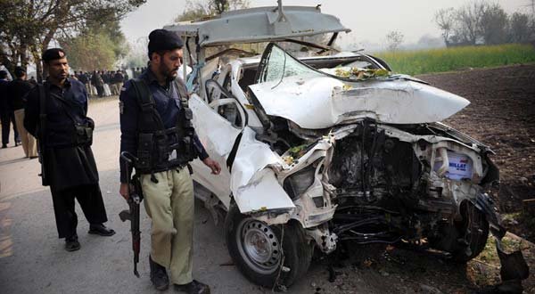 Police officials examine the wreckage of a bomb disposal vehicle after a roadside bomb explosion on the outskirts of Peshawar on Monday.
