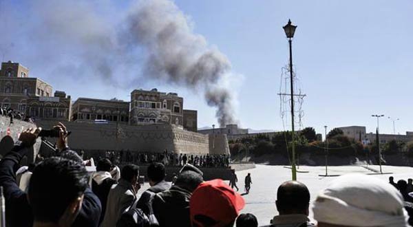 Bystanders watch as smoke rises after an explosion at the Defense Ministry complex in Sanaa, Yemen, on Thursday. (AP Photo/Mohammed Hamoud)