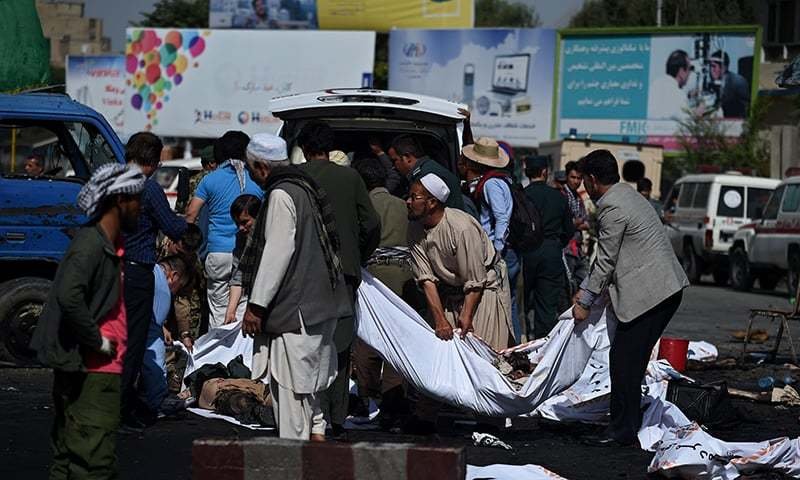 Afghan volunteers carry the bodies of victims at the scene of a suicide attack that targeted crowds of minority Shiite Hazaras during a demonstration at the Deh Mazang Circle of Kabul. — AFP