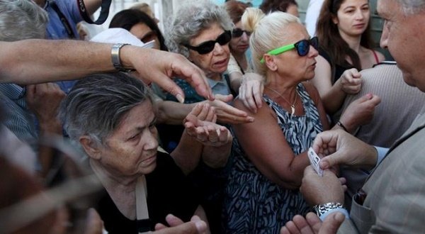 Pensioners are given priority tickets by a National Bank branch manager (R), as they wait to receive part of their pensions in Athens, Greece July 13, 2015. Euro zone leaders clinched a deal with Greece on Monday to negotiate a third bailout to keep the near-bankrupt country in the euro zone after a whole night of haggling at an emergency summit.   REUTERS/Yiannis Kourtoglou