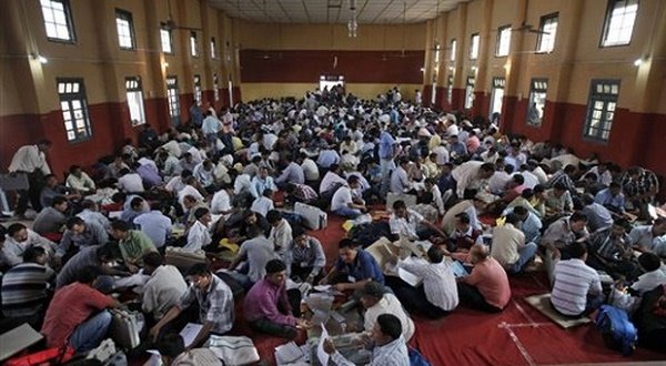Polling officials sit inside a hall of a school as they inspect the performances of electronic voting machines and other election material before heading to their  polling stations on the eve of the first phase of General elections in Dibrugarh, Assam, . AP Photo/Altaf Qadri
