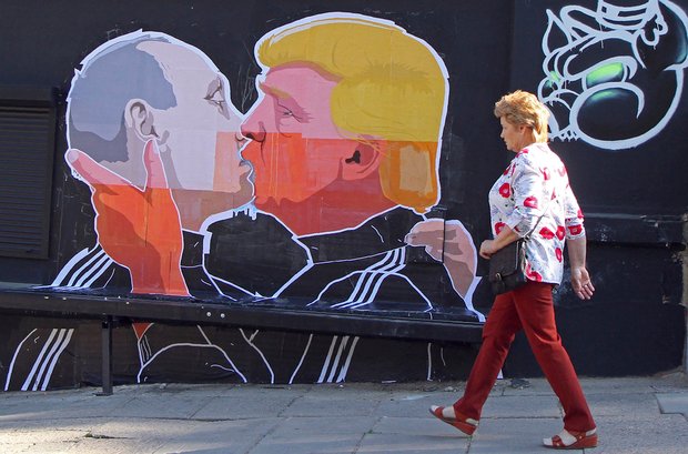 A woman walks past a mural on a restaurant wall depicting US Presidential hopeful Donald Trump and Russian President Vladimir Putin greeting each other with a kiss in the Lithuanian capital Vilnius on May 13, 2016. Kestutis Girnius, associate professor of the Institute of International Relations and Political Science in Vilnius university, told AFP -This graffiti expresses the fear of some Lithuanians that Donald Trump is likely to kowtow to Vladimir Putin and be indifferent to Lithuaniaís security concerns. Trump has notoriously stated that Putin is a strong leader, and that NATO is ëobsolete and expensive.í / AFP PHOTO / Petras Malukas
