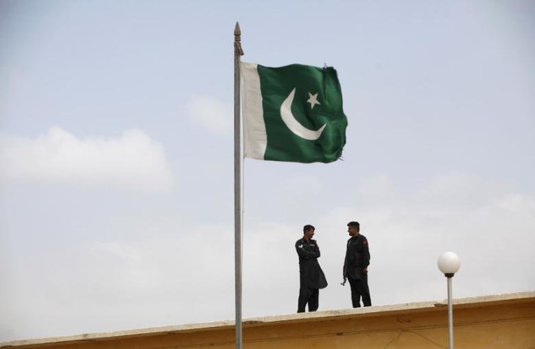 A Pakistani flag flies on a mast as paramilitary Frontier Corps soldiers talk while guarding at Karachi's District Malir prison, August 23, 2013. REUTERS/Akhtar Soomro