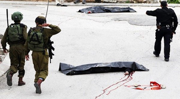 Israeli soldiers and policemen pass by the body of a Palestinian who was allegedly shot in the head when he approached an Israeli check post in this March 24 photograph. AFP