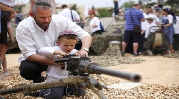 An Israeli man shows his son how to work a machine gun during a traditional military weapon display to mark the 66th anniversary of Israel's Independence at the West Bank settlement of Efrat on May 6, 2014 near the biblical city of Bethlehem.  TIBBONGALI TIBBON/AFP/Getty Images