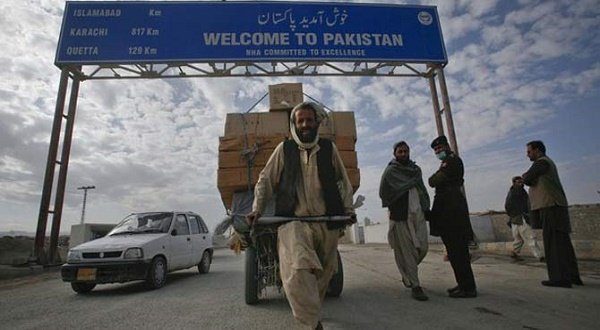 A Pashtun man passes a road sign while pulling supplies towards the Pakistan-Afghanistan border crossing. Reuters photo.