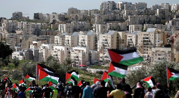 Peace activists raise Palestinian flags as they protest against the illegal Jewish settlements that continue to expand on Palestinian land occupied by Israel. 