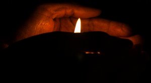 Hands holding a candle during a candle light vigil with copy space