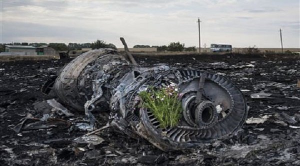 Flowers are placed on a plane engine at the crash site of a Malaysia Airlines jet near the village of Hrabove, eastern Ukraine, Saturday, July 19, 2014. Credit: AP